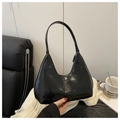 Detail of a black patent leather crescent underarm bag held by hand with glossy finish - Black