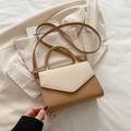 Bolso bandolera marrón con solapa tejida crema y correa ajustable sobre una chaqueta - Caqui