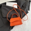 Minimalist orange small square bag with top handle and crossbody strap on black blazer - Orange