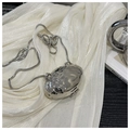 Dettaglio di una borsa ovale argentata con texture metallica martellata e catena a serpente - Argento