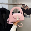 Pink semi-circle tote bag with top handle and gold lock closure in a stylish studio setting - Pink