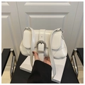 Close-up of white glossy shoulder bag with a large silver horseshoe buckle detail - White