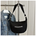Detail of a black canvas crescent tote bag with YICAIAINI text hanging on a rack - Black