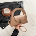 Chic beige semi-circle handbag with gold lock and top handle in a lifestyle setting - Khaki
