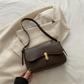Minimalist dark brown crossbody bag with gold hardware on beige blazer background - Brown