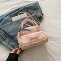 Roze schelptas met kant en strik, gepresenteerd als crossbodytas op een zacht bed - Roze