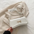 Bolso baguette blanco con hebilla de lazo dorado y correa anudada sobre blazer beige - Blanco