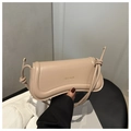 Detalle de bolso de cuero beige con solapa ondulada y texto XM & BAGS en dorado - Caqui