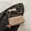 Sac à bandoulière chic marron clair en cuir avec un nœud doré sur une veste grise - Kaki