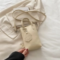 Vertical cream-colored faux leather crossbody bag with a cute puppy charm and top handle - White