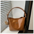 Detail of glossy brown bucket bag featuring a metal bow and cute bear keychain charm - Brown (With Pendant)