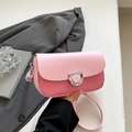Sac bandoulière rose clair avec boucle en D argentée, porté à la main par un mannequin - Rose