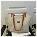 Detail of V-shaped woven texture on straw tote bag with brown leather handles and tag - Brown
