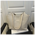 Detailed macro view of woven straw texture and leather fashion patch on beige tote bag - White