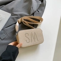 Beige camera bag with studded SM logo and wide nylon shoulder strap on white desk - Gold