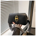 Close-up of black leather handbag with large gold buckle and patterned jacquard strap - Black