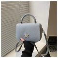 Detalle de un bolso de mano azul claro con una estrella plateada brillante y textura tejida - Azul
