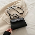 Elegante borsa a mano squadrata nera con fibbia in metallo argento su sfondo crema - Nero