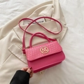 Pink crossbody handbag with crocodile texture and gold M logo on a beige blazer - Fuchsia