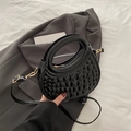 Glossy black crocodile pattern handbag with golden zipper on grey blazer background - Black