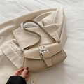 Minimalistische beige Umhängetasche mit großer Metallschnalle auf einem Blazer - Khaki