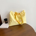 Pale yellow minimalist tote bag with red lettering on a dark wood table - Yellow