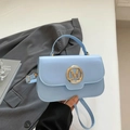 Borsa a tracolla retrò azzurra con fibbia M dorata su sfondo di abito grigio - Blu