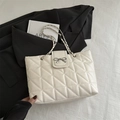 White quilted tote bag with silver bow detail and chain strap for stylish commuting - White