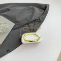 Borsa ovale bianca con manico in metallo dorato su sfondo estetico grigio moderno - Bianco