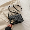 Chic black quilted crossbody bag with gold buckle on a minimalist urban background - Black