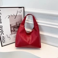 Modische rote geflochtene Lederhandtasche mit integriertem Schultergurt auf weißem Sockel - Rot