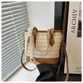 Detail of woven straw bucket bag featuring brown leather trim and white lace ribbon - Brown