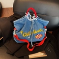 Bolso tote de mezclilla azul con bordado Chill vibes y asas rojas en silla de cuero - Azul claro