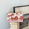 Chic crossbody bag with pink and white cow print flap and gold circular ring handle - Pink