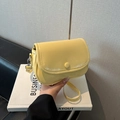 Glossy light yellow crossbody flap bag with silver hardware on business layout book - Yellow
