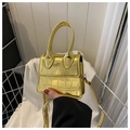 Vue détaillée du mini sac à main doré avec motif crocodile tenu à la main pour échelle - Doré