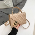 Quilted beige crossbody bag with gold chain lock on a grey suit jacket background - Khaki