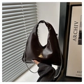 Primer plano de bolso de cuero oscuro brillante con elegante cadena de metal plateado - café