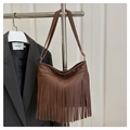 Dettaglio della borsa tote marrone scuro con frange e borchie metalliche su un rack - Marrone