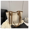 Detail van een grote wit-bruine leren draagtas in een minimalistische lifestyle setting - Wit