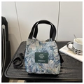 Close-up of floral brocade tote bag with green label on black table with art book - Style 5