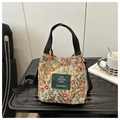 Detail of floral tapestry bucket bag with adjustable strap on a dark wooden table - Style 3