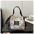 Floral canvas tote bag with adjustable shoulder strap and green label on textured table - Style 1
