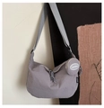 Detail of grey nylon crossbody bag featuring a wide strap and a round coin purse charm - Gray