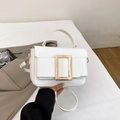 White square handbag with gold buckle and adjustable strap in a stylish minimal setting - White