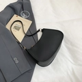 Minimalist black matte leather crescent underarm bag with metal buckle on grey blazer - Black