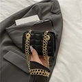 Mini black quilted leather crossbody bag with golden chain strap on stylish blazer - Black