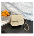 Close-up of white floral embroidery and gold metal clasp on a straw saddle bag - Khaki