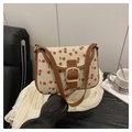 Close-up of cherry pattern canvas bag with brown leather trim and metal clasp detail - Brown