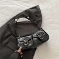 Minimalist black glossy shoulder bag with silver buckles and flap pockets on grey blazer - Black